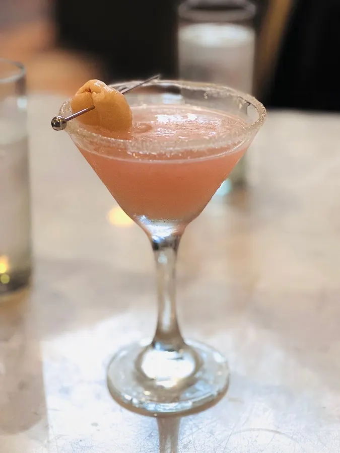 A pink martini with a sugared rim and dried apricot