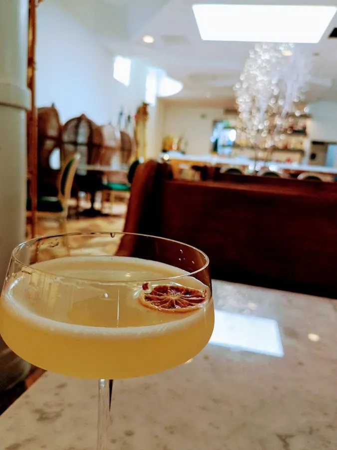 A golden cocktail in a coupe with a dried citrus wheel