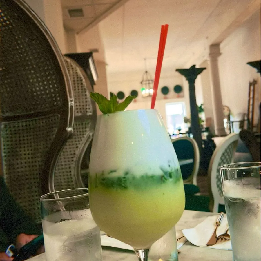A layered green and white cocktail with mint, in the dining room
