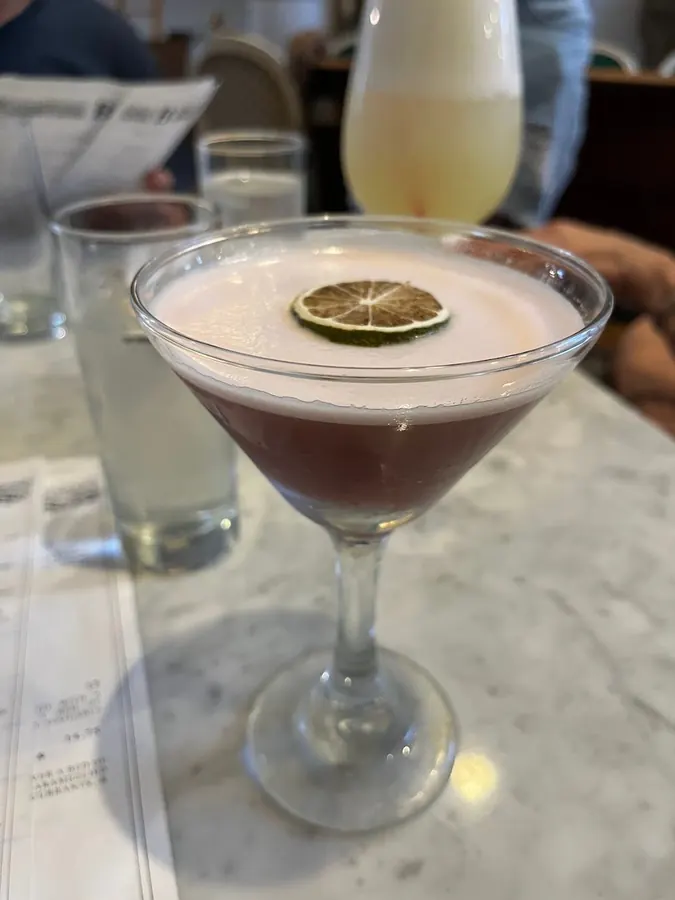 A foamy purple sour with a lime wheel