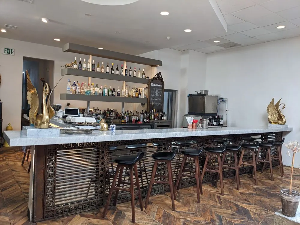 The long marble bar with gold swans and a wall of bottles