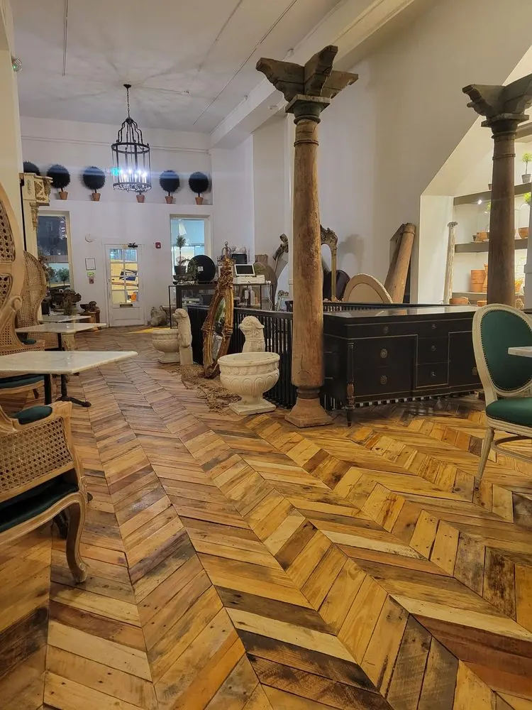 The reclaimed-wood herringbone floor leading to the front room, with carved columns and a lantern chandelier